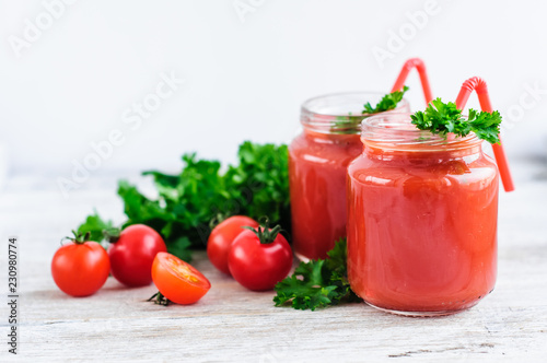 tomato juice in glass jars with cherry tomatoes on a wooden table