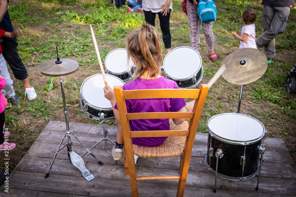 Ragazzina seduta che suona la batteria in un parco Stock Photo Adobe