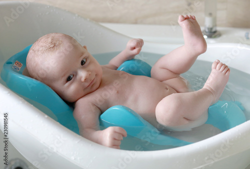 Foto Bébé garçon blond dans son bain tout content avec un grand sourire
