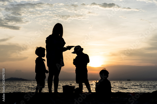 The silhouette of kids and mother at the beach in evening.