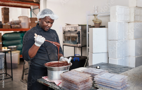 Fototapeta Worker using a bain marie to melt chocolate