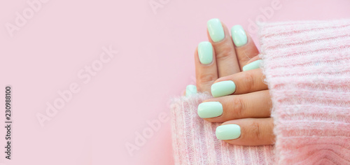 Tender hands with perfect blue manicure on trendy pastel pink background. Place for tex photo