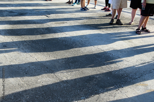 Shadows on the asphalt people standing in line, form a picture of the road markings pedestrian crossing