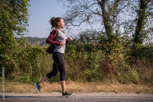 Fototapeta Naklejka Na Ścianę i Meble -  woman jogging along a country road