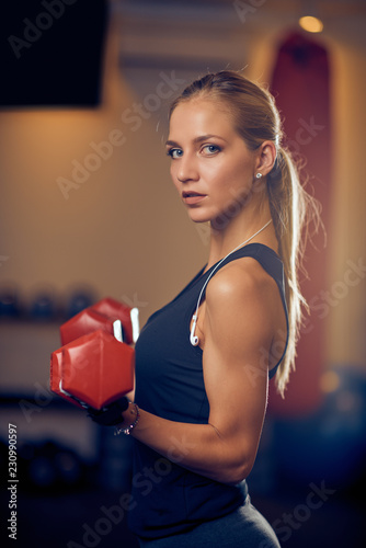 Woman lifting dumbbells and looking at camera. Side view. Healthy lifestyle concept. © chika_milan