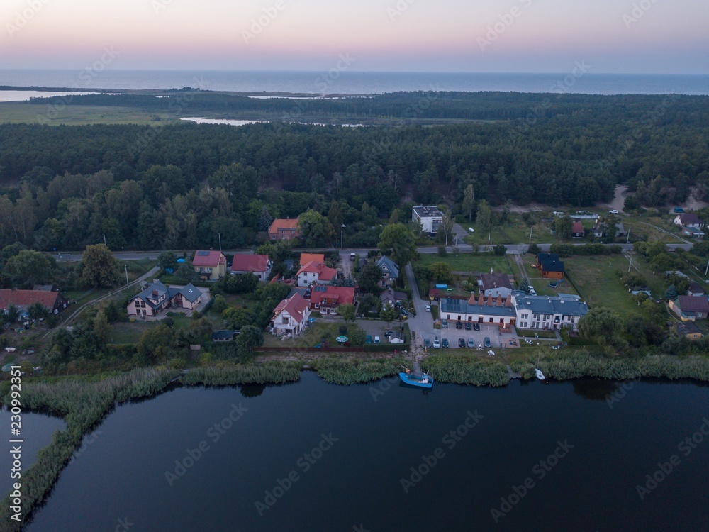 Obraz premium Beautiful sunset over estuary of Vistula river in Gdansk. Summer sunset over sea and river and small village.