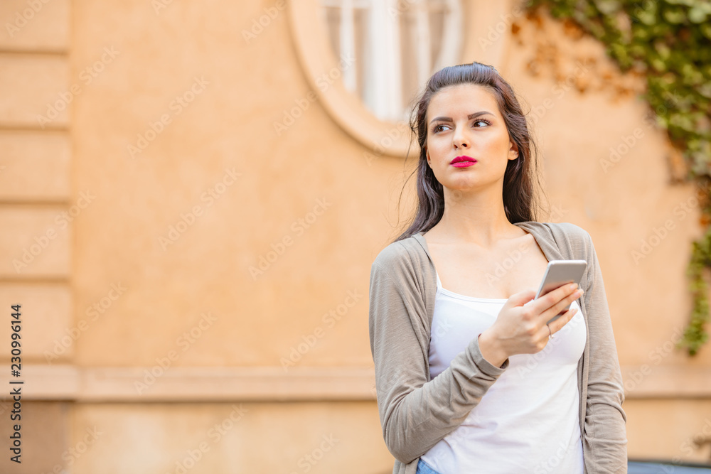 Cute young woman using cellphone in urban surroundings. Cute young woman using cellphone in urban surroundings.
