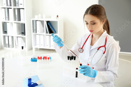 Female doctor dripping blood into test tube in laboratory