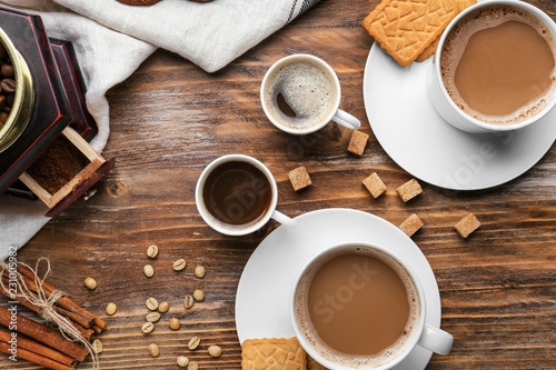 Cups with tasty aromatic coffee and cookies on wooden table