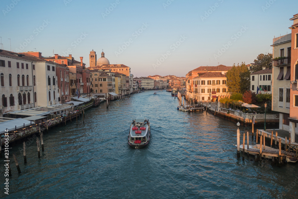 Venice , Italy - October 17 2018: Sailing on a wooden boat through venice on a bright day with a clear blue sky.