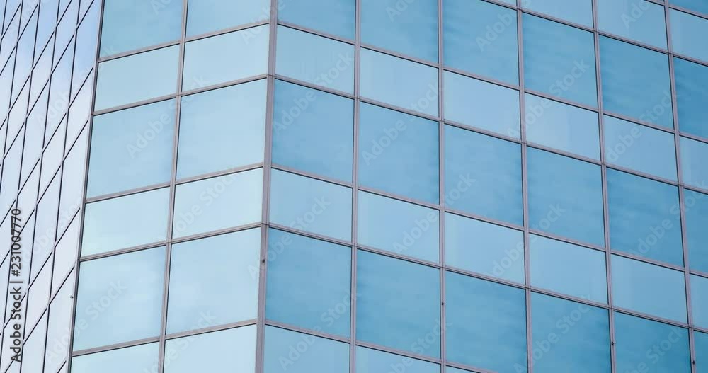 4k time lapse shot with vertical tilt of a glass office building facade reflecting moving clouds. 4k time lapse shot with vertical tilt of a glass office building facade reflecting moving clouds.