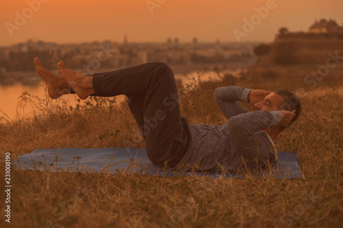 Man exercising on sunset with city view.