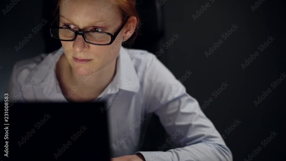 Young businesswoman works behind a computer late in the evening. Young businesswoman works behind a computer late in the evening.