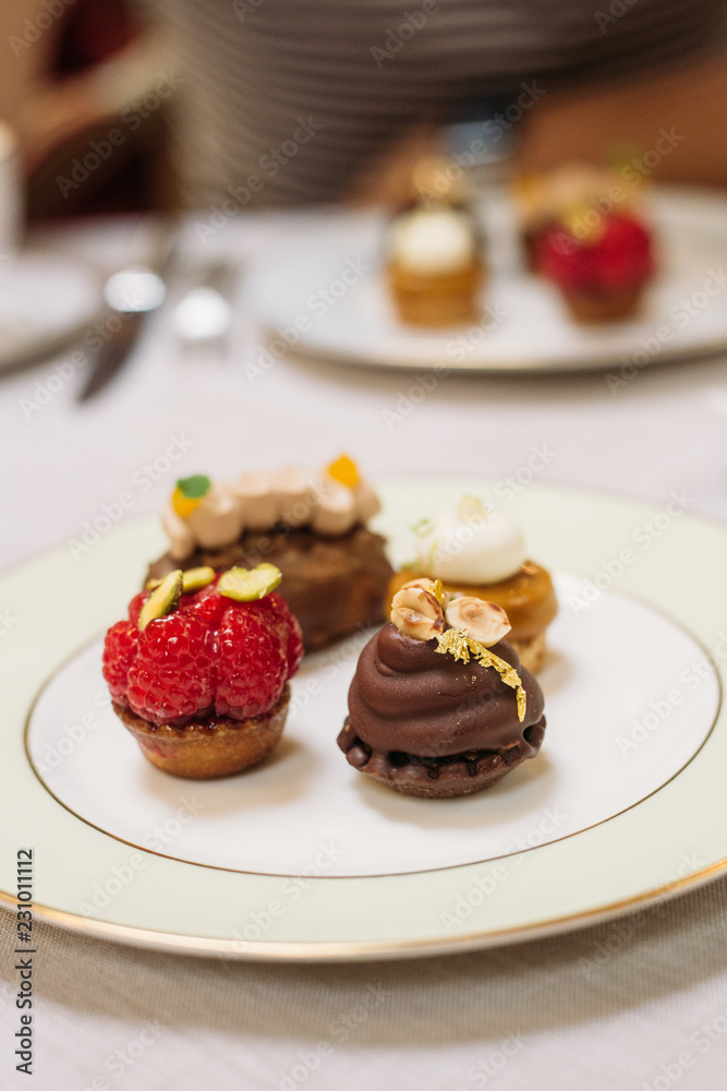 Different Kind of Small Cakes on the Plate, Traditional English Tea Ceremony in Luxury Hotel Different Kind of Small Cakes on the Plate, Traditional English Tea Ceremony in Luxury Hotel