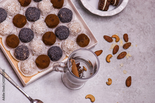Round candies and brown biscuit on a gray table. Sweets with poppy seeds, coconut, chocolate.