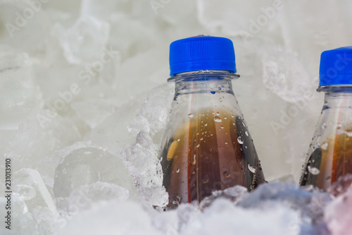  soda in cold of plastic bottle with blue Bottle Caps on ice