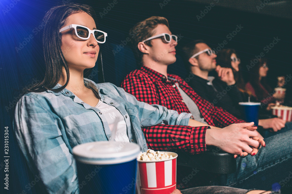 Naklejka premium Calm and relaxed students are watching movie. They are sitting together in one row. People are very happy.