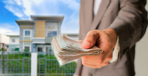 Businessman giving money with blurred home