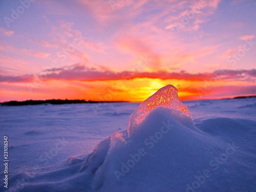 Obraz na płótnie Transparent piece of ice on the snow against the backdrop of a winter sunset w salonie