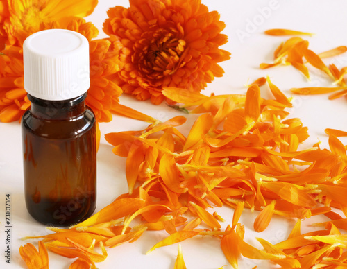 Closeup of organic oil with common marigold on a white background .Medicinal herb. Healthy concept.