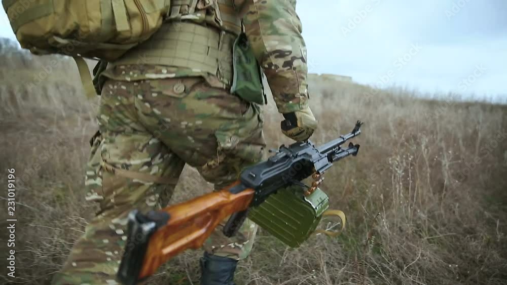 Armed soldiers running forward to attack. Group of military men running on field. Soldiers team run forward to attack enemy at fields. camera in motion follows the machine gun, close up.