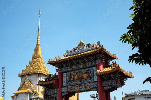 Architectural detail of Buddhist temple, Wat Traimit and Chinatown Gate over blue sky in Bangkok, Thailand