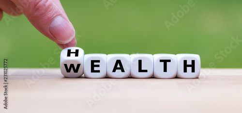 Hand is turning a dice and changes the word "Health" to "Wealth"