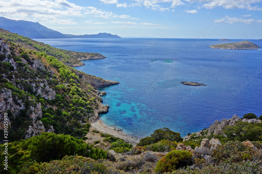 Fototapeta premium Einsame Badebucht mit blauem Himmel und türkisfarbenem Wasser unter dramatischem Himmel mit Wolken