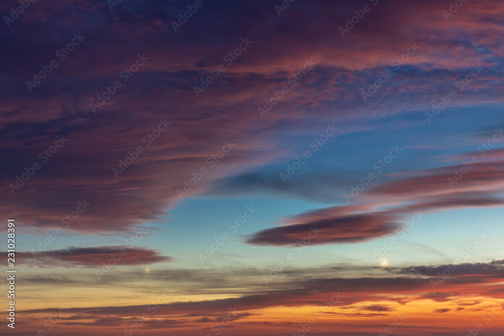 Dramatic colored sky at sunset. Moon and star in the clouds.