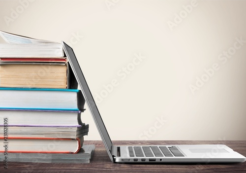 Stack of books with laptop on table