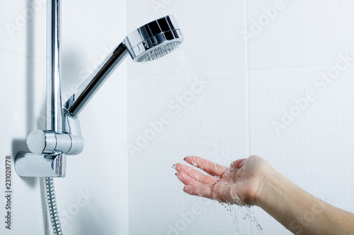the hand of the girl reaches for the silver shower which stands in the holder. splashing