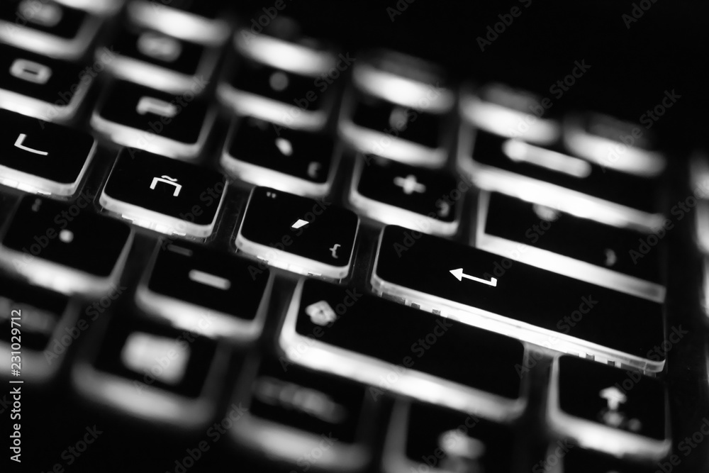 Closeup of laptop keyboard illumination, backlit keyboard. White light