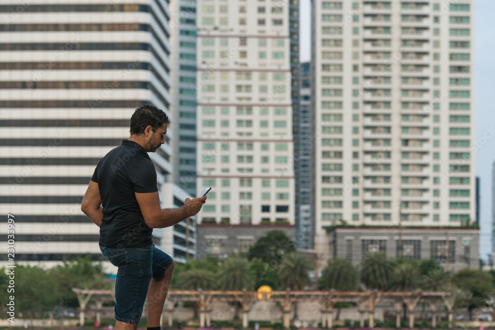 Man holding a smart phone with buildings in the city in background
