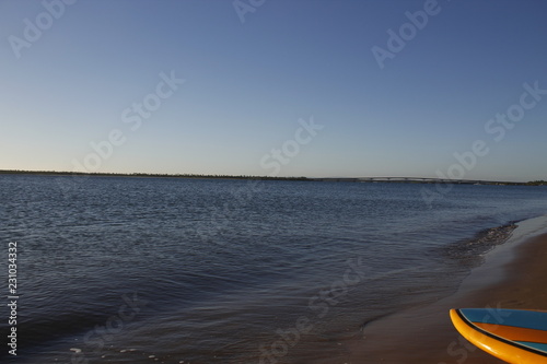 Awesome sunset in front of the beach with clean blue sky with stand up paddle on the sand