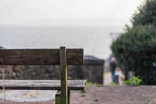 An empty bench looks out over an out of focus view of the sea