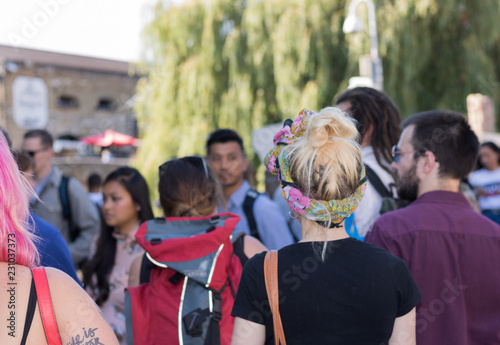 Modern young woman with casual hairstyle is walking along a busy cosmopolite urban street among different people. 