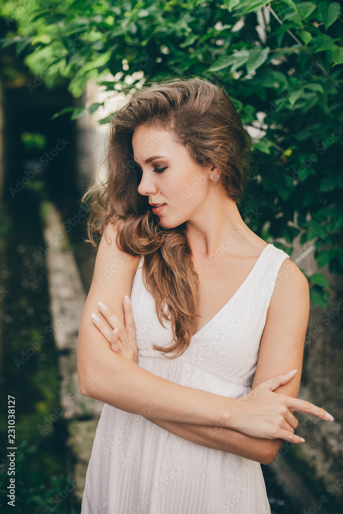 Beautiful happy girl with curly natural hair in white dress near green tree leaves. Summer beauty portrait. Dreamer lady enjoy nature. Inspired woman with dreamy sight in long tunnel in forest. Beautiful happy girl with curly natural hair in white dress near green tree leaves. Summer beauty portrait. Dreamer lady enjoy nature. Inspired woman with dreamy sight in long tunnel in forest.