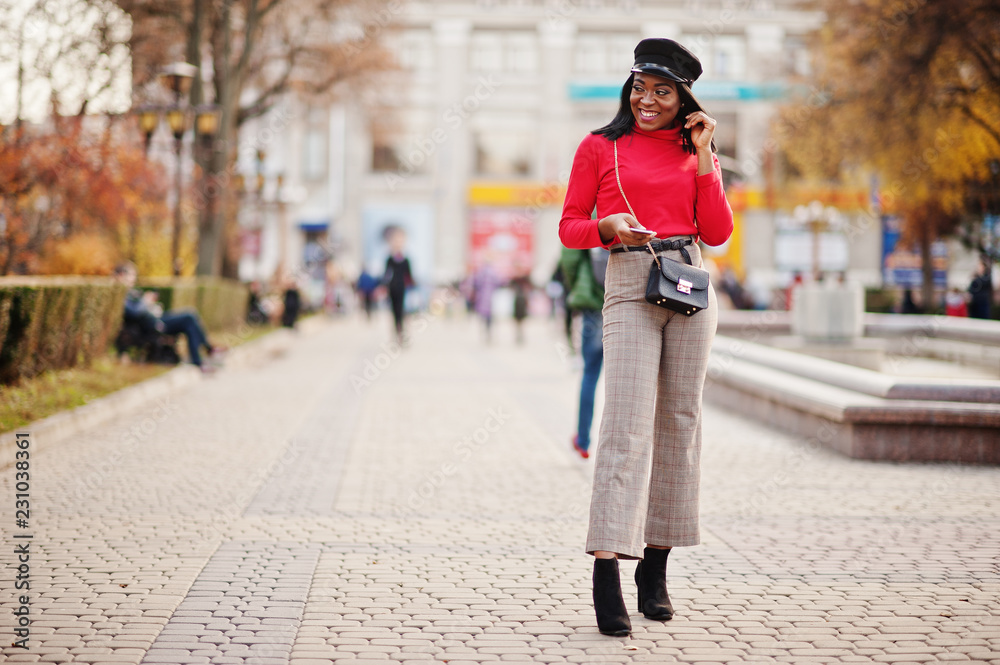African american fashion girl in newsboy cap and handbag posed at street.