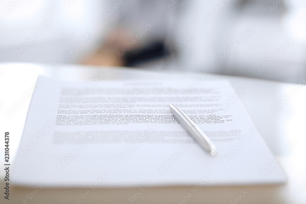 Obraz premium Contract with a pen and blurred business people on the background, close-up