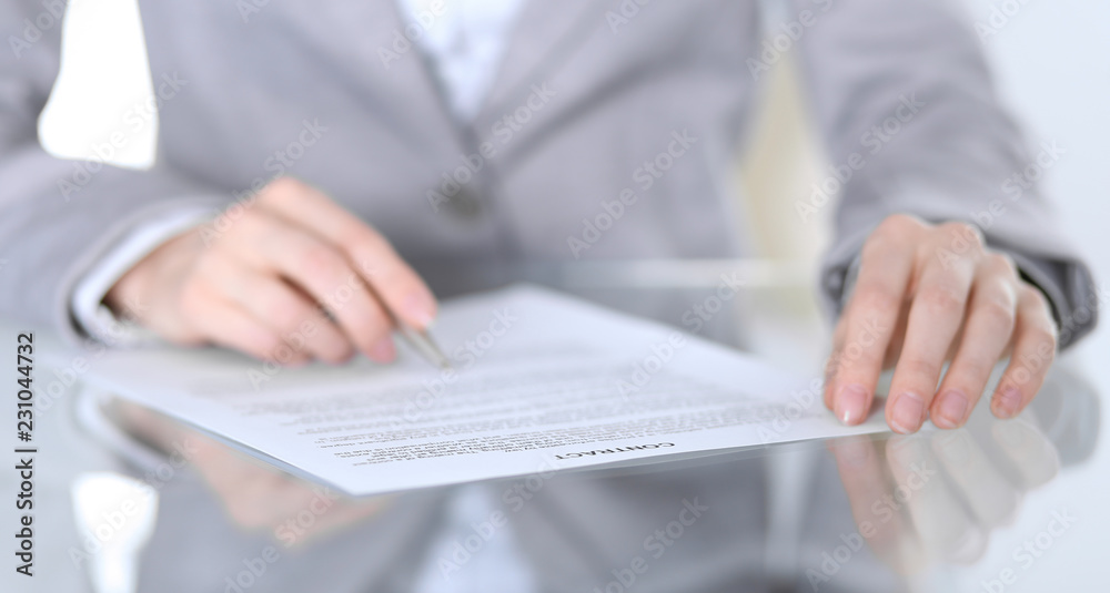 Close-up of female hands with pen over document, business concept. Lawyer or business woman at work in office Close-up of female hands with pen over document, business concept. Lawyer or business woman at work in office