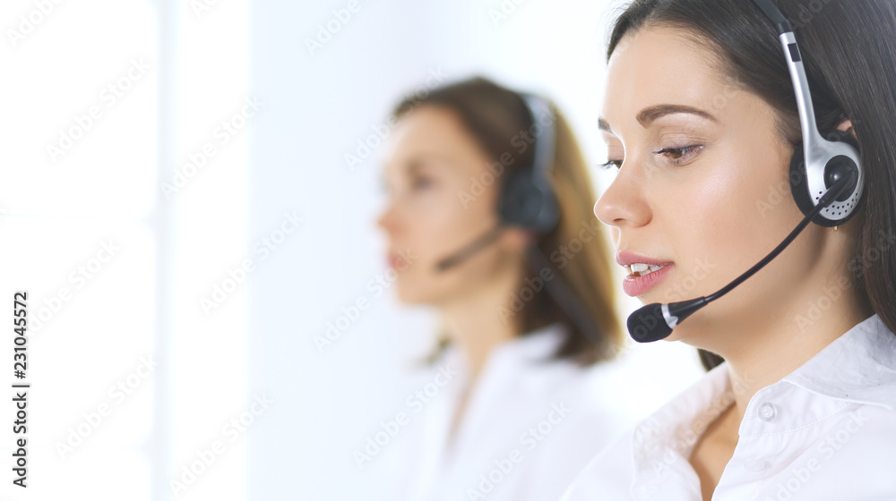 Group of call center operators at work. Focus at beautiful business woman in headset Group of call center operators at work. Focus at beautiful business woman in headset