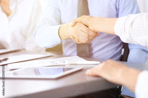 Close-up of business handshake at meeting or negotiation above the desk in office. Partners shaking hands while satisfied because signing contract or financial papers.  Success concept © rogerphoto