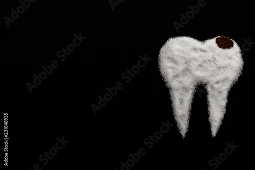 tooth made of sugar on a black background with caries