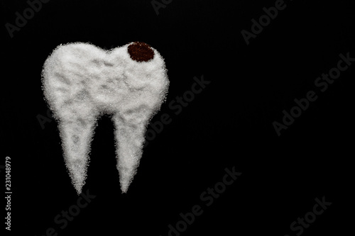 tooth made of sugar on a black background with caries