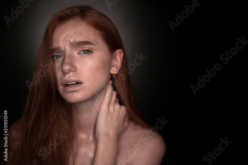 Displeased young redhead girl woman with pain in the neck with healthy glow wet skin posing isolated over black wall background looking camera near empty copyspace touching neck.