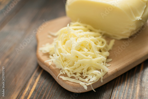 Grated cheese for cooking on a wooden background.