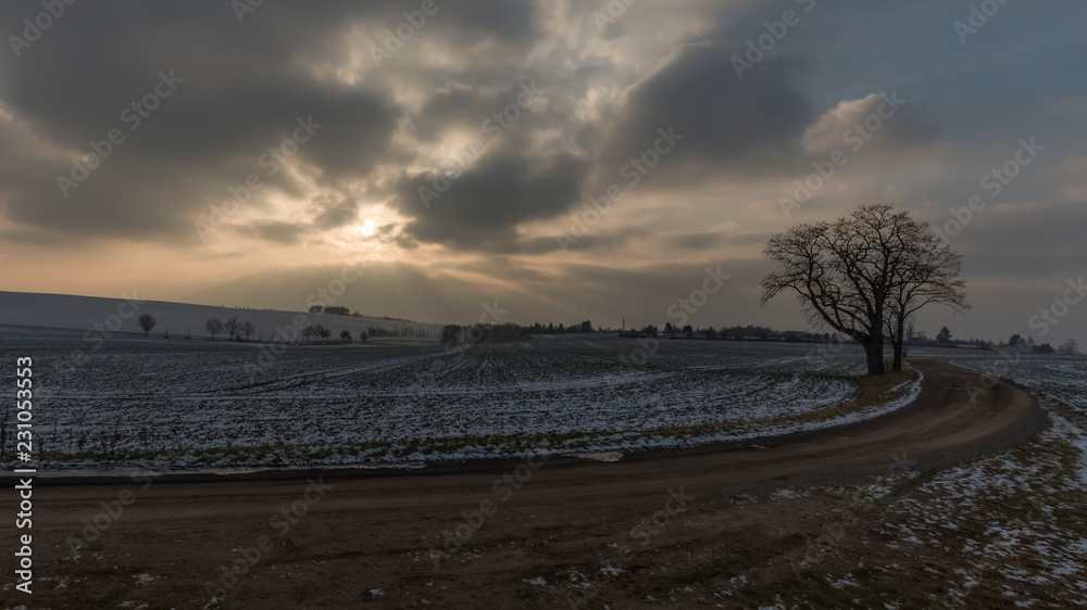 dark clouds and sun in winter landscape