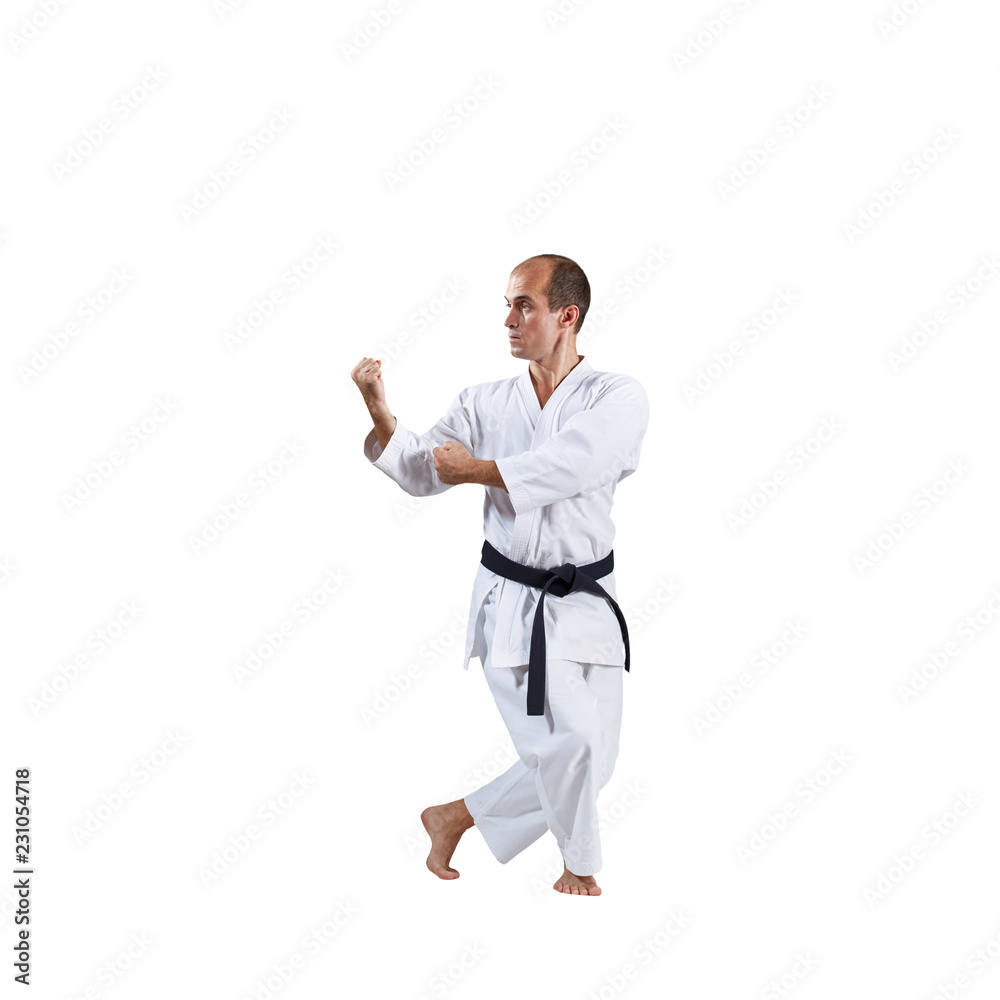 On a white background, an active adult athlete trains formal karate exercises. On a white background, an active adult athlete trains formal karate exercises.