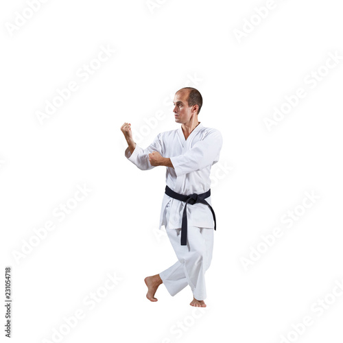 On a white background, an active adult athlete trains formal karate exercises.