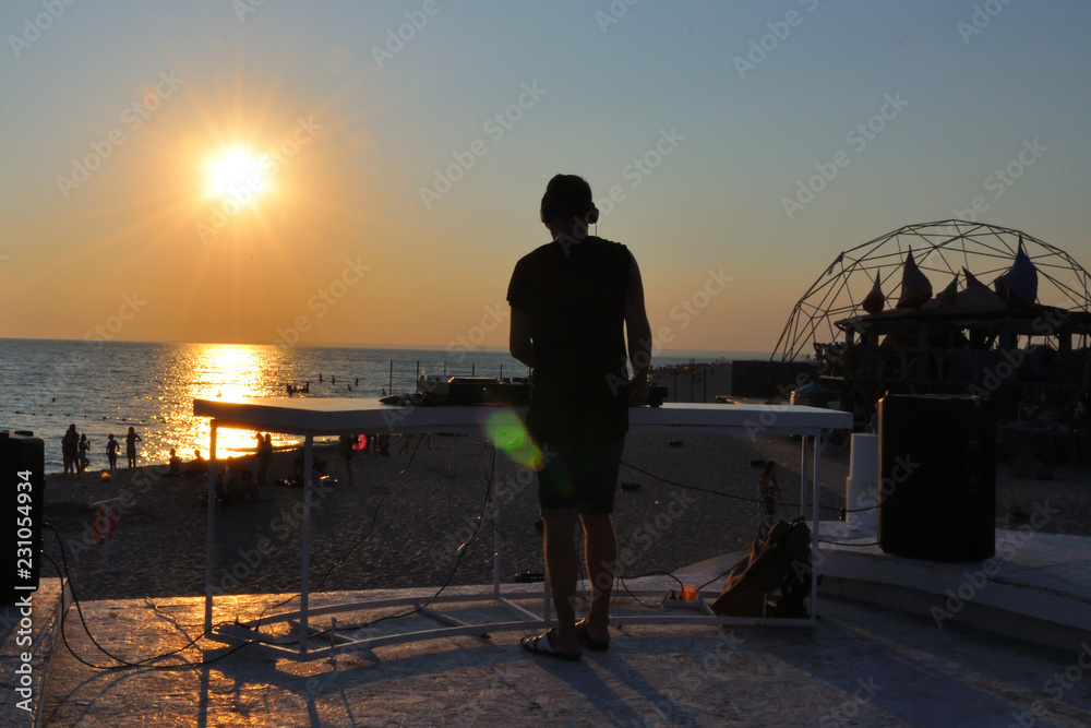 Fototapeta premium DJ plays music on the beach at sunset